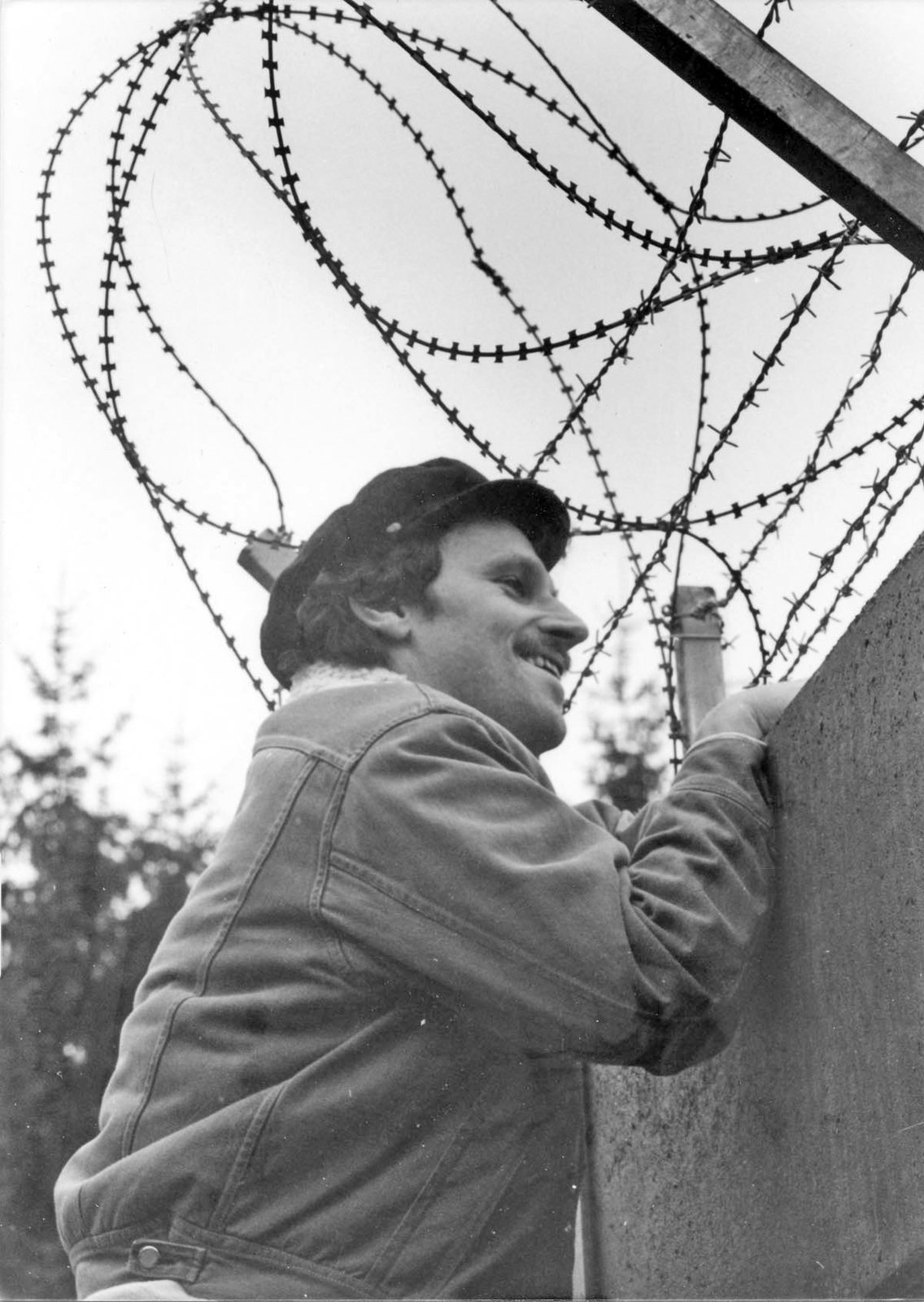 Ein Mann blickt über die mit Stacheldraht gesicherte Betonmauer der Raketenstation